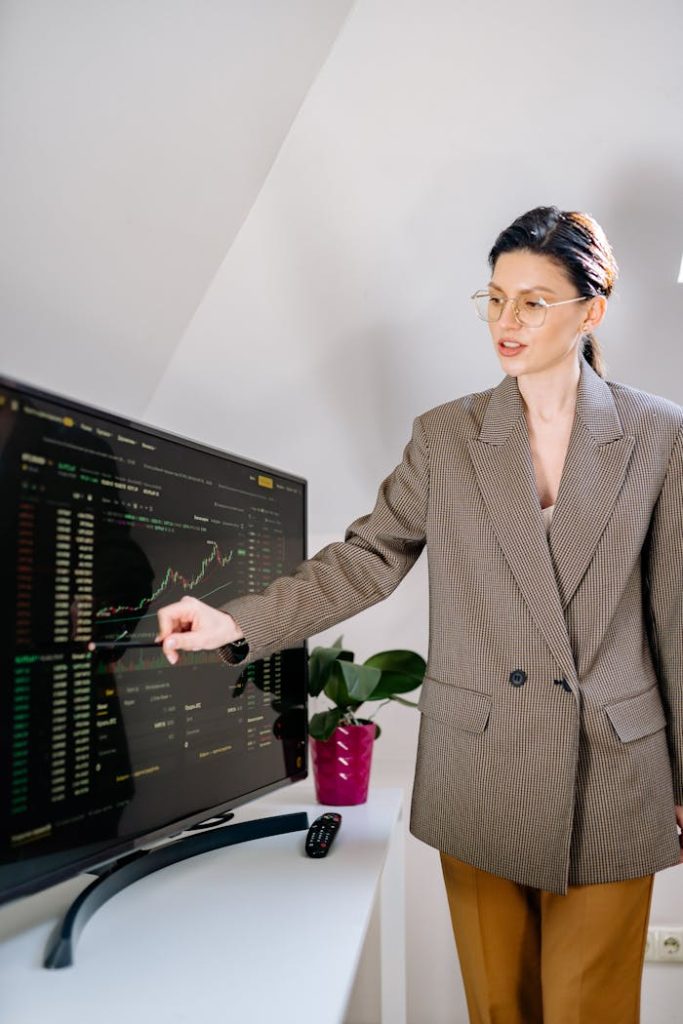 A professional woman in an office analyzing cryptocurrency charts on a monitor.